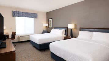 A hotel room with two beds, a desk, and a chair.