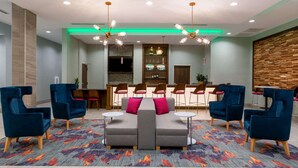 Un hall d’entrée moderne avec un canapé modulable, des fauteuils bleus et un coin bar.