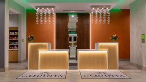 Un espace d’accueil doté de deux comptoirs, d’un plafond éclairé en vert et d’une porte centrale.