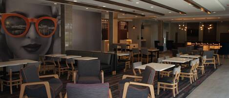 A modern restaurant with booths and tables, featuring a large mural and contemporary lighting.
