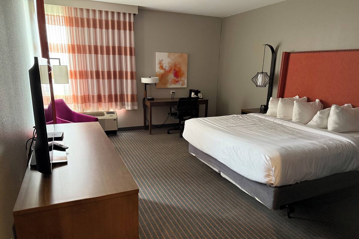 Een hotelkamer met een bed, bureau, stoel en lamp.