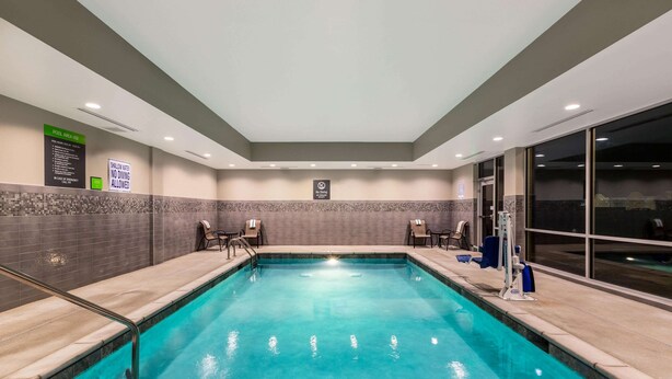 Une piscine intérieure à l’eau claire, avec des murs carrelés et un panneau indiquant qu’il est interdit de plonger.
