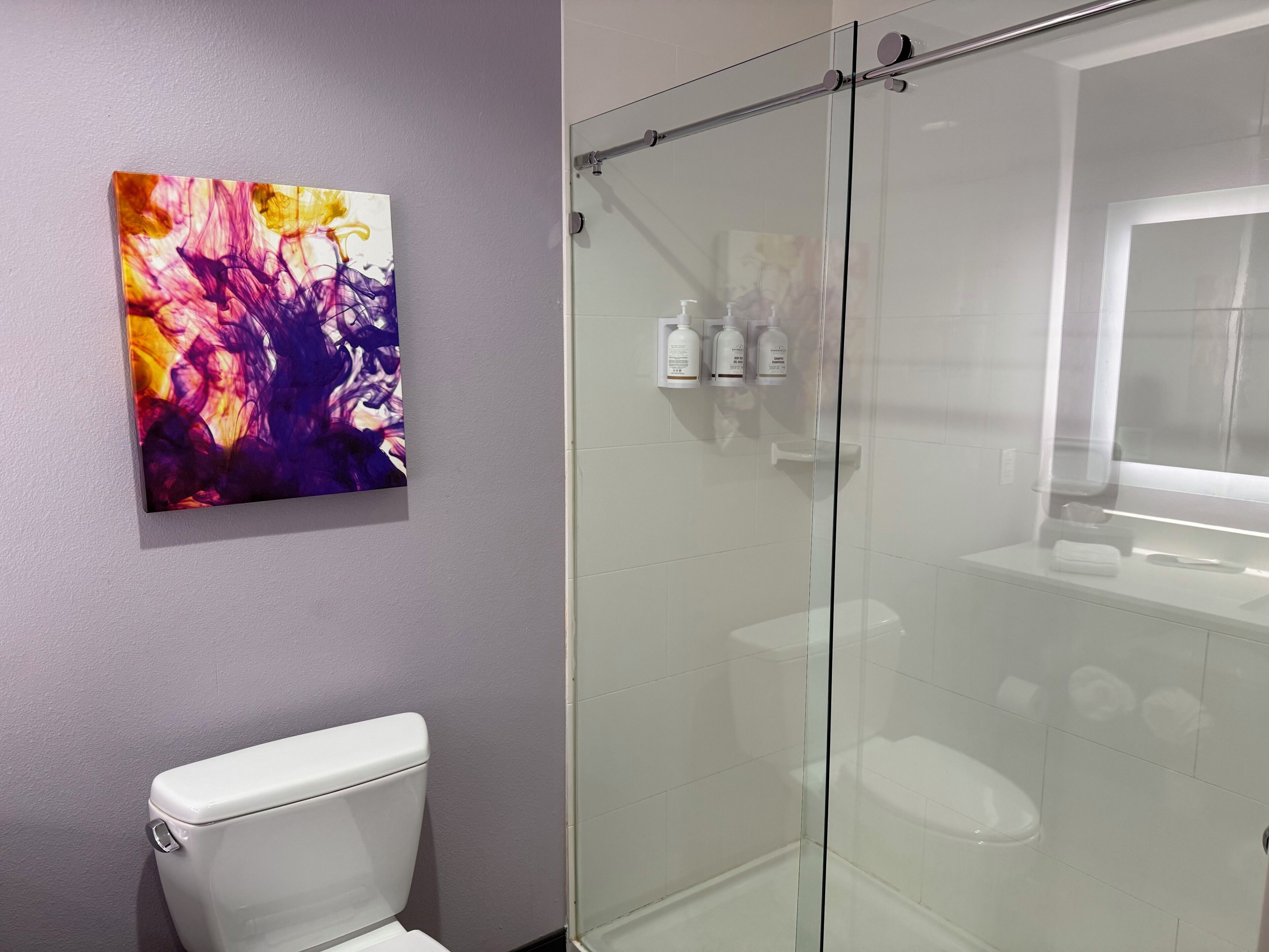A bathroom with a glass-enclosed shower, a white toilet, and a wall-mounted sink.