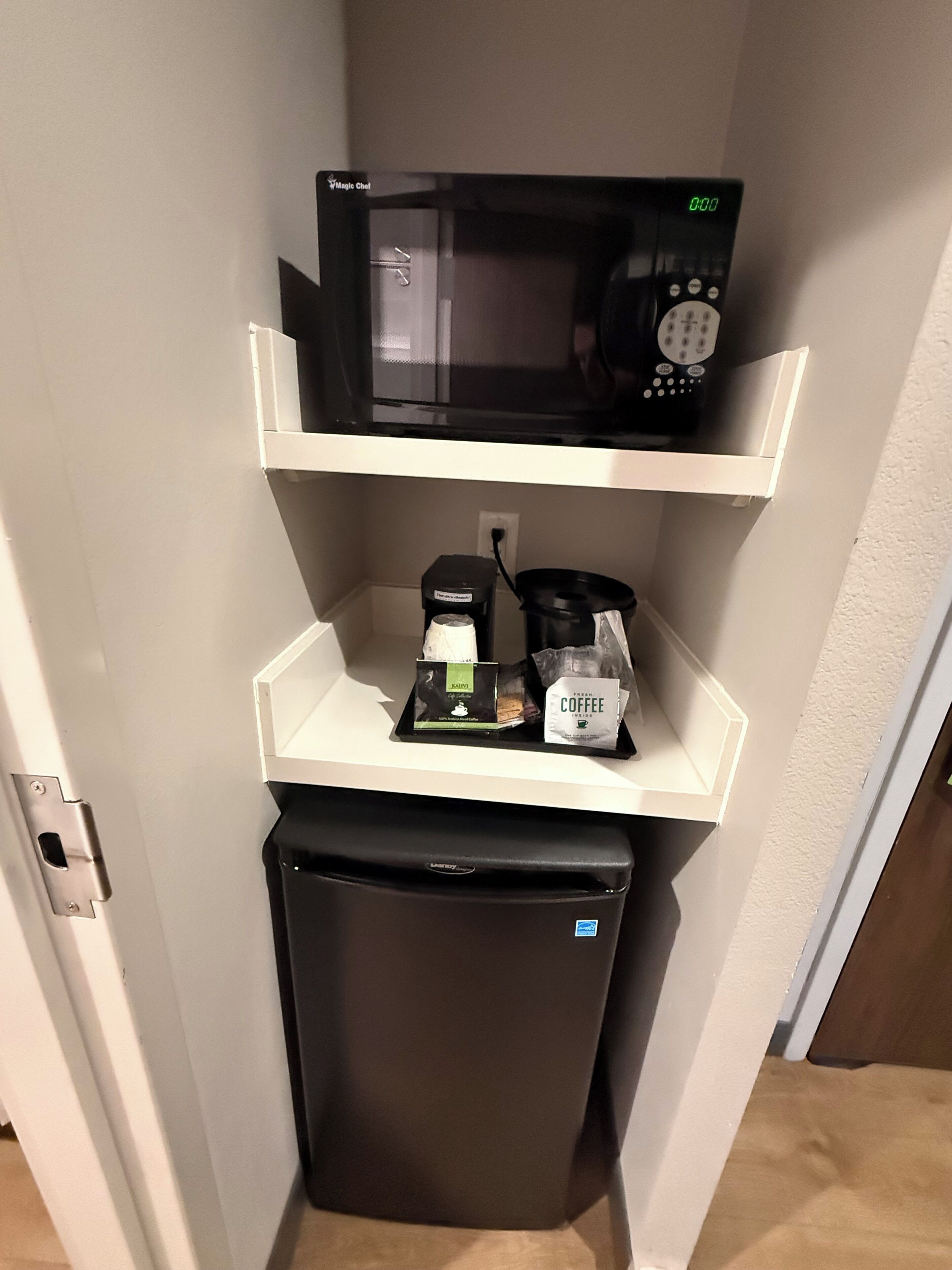 A compact kitchenette with a microwave, coffee maker, and a small refrigerator.