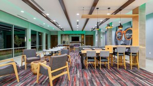 Un espace de détente moderne offrant différents types de sièges, notamment des canapés et des fauteuils, un bar et un grand téléviseur à écran plat.