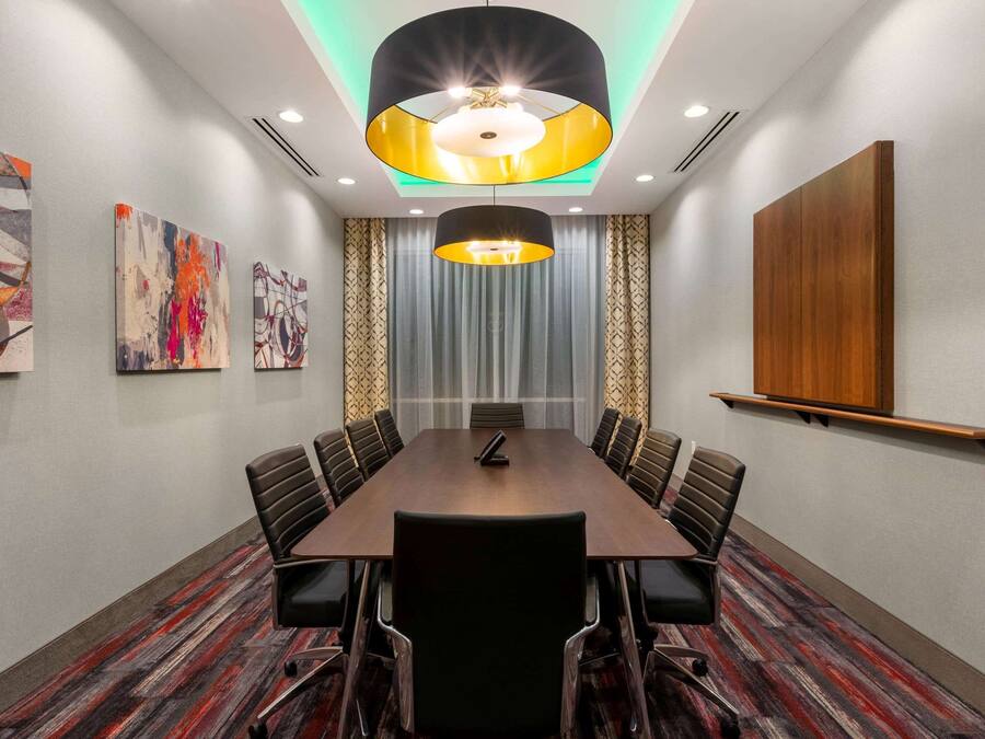 Une salle de conférence avec une longue table, des chaises, un pupitre et des œuvres d’art abstrait accrochées aux murs.