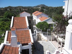 A residential area with terracotta-tiled roofs, white walls, and a stone staircase leading to a gated entrance. - Castellino - Traditional Loft Apartment with balcony for 5 people (Faliraki)
