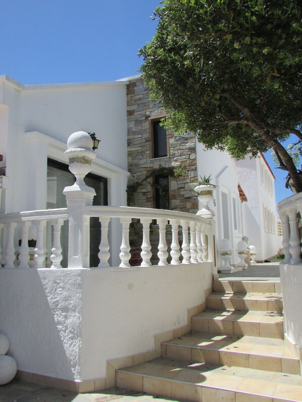 A white building with a stone facade, a white balcony with balusters, and a tree in the background. - Castellino - Traditional Loft Apartment with balcony for 5 people (Faliraki)