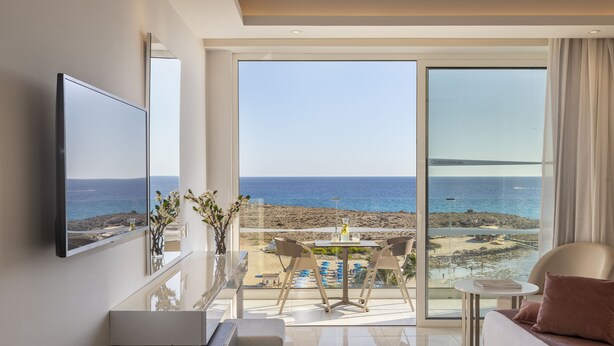 Ein modernes Hotelzimmer mit Balkon, Essbereich und Fernseher.