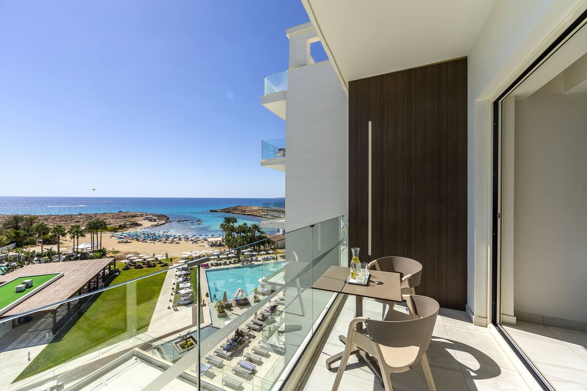 Un balcón con vista a la playa y la piscina.
