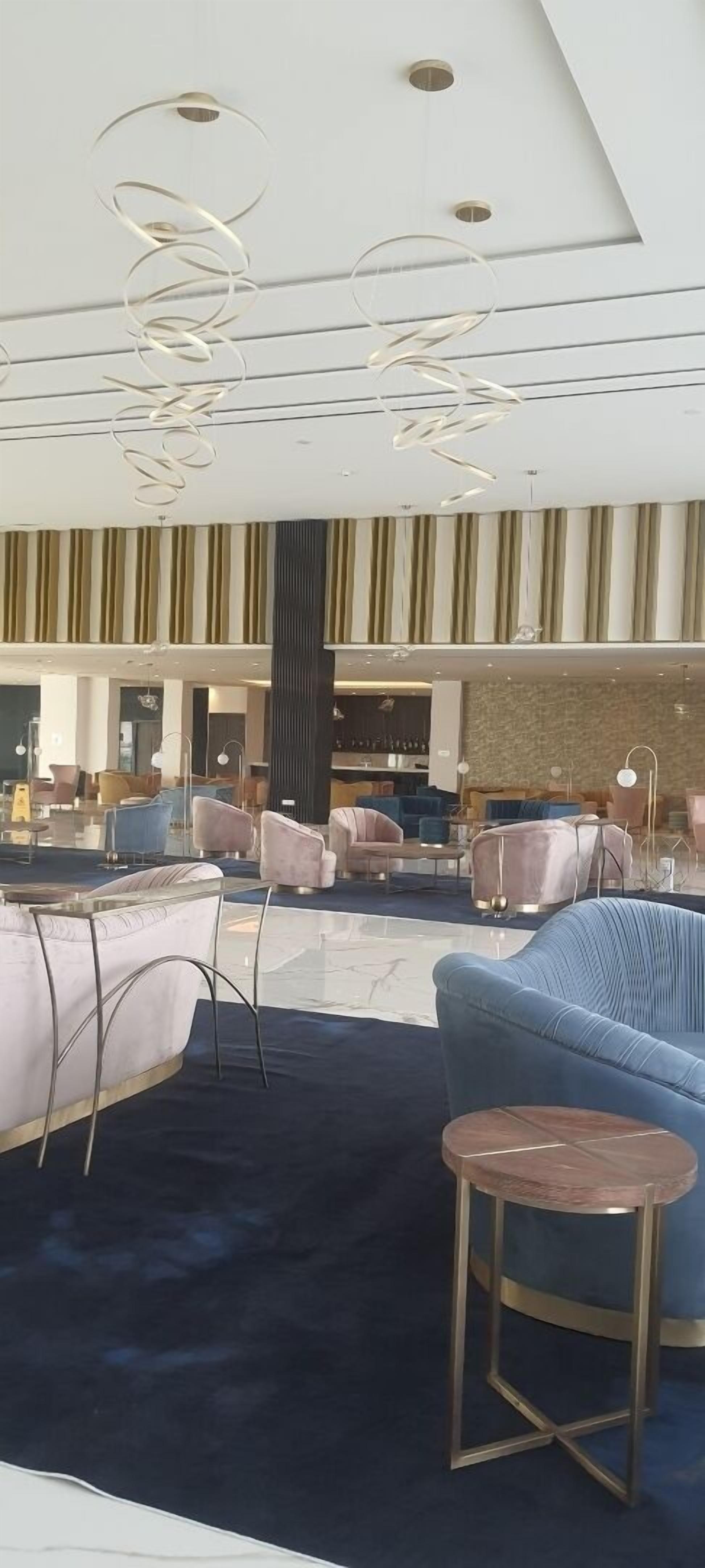 A modern lobby with a blue sofa, a round wooden table, and a patterned rug.