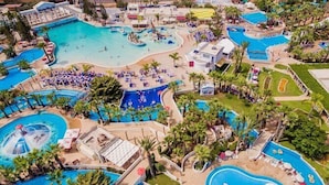 Vue aérienne d’un complexe hôtelier doté de plusieurs piscines, de chaises longues et de palmiers.