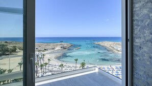 Ein Balkon mit freiem Blick auf einen Strand, Palmen und das Meer.