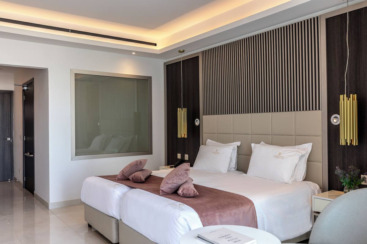 Una habitación de hotel moderna con una cama grande, una mesita de noche y un amplio ventanal.