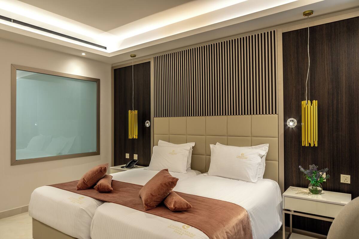 Una habitación de hotel moderna con una cama grande, una mesita de noche y un ventanal amplio.