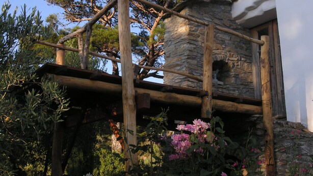 A rustic stone building with a wooden balcony supported by beams.