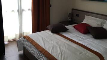 Camera d'hotel con un letto grande, un quadro appeso alla parete e vista sull'esterno dalla finestra.