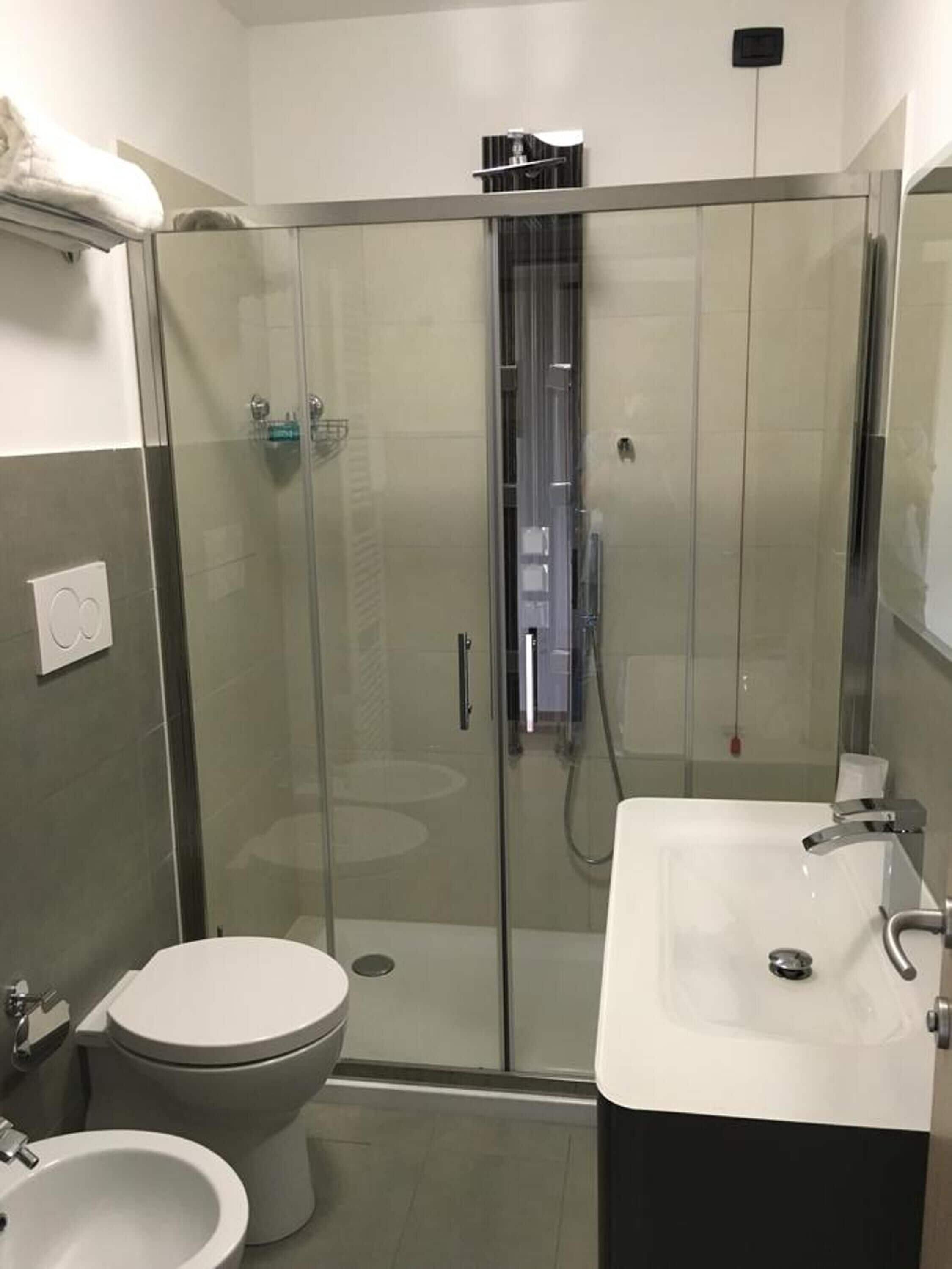 Une salle de bain moderne avec une douche à parois de verre, un lavabo blanc et des toilettes.