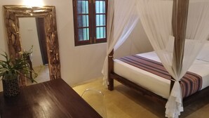 Een kamer met een bed onder een baldakijn, een houten tafel, een spiegel en een raam met een decoratieve roede.