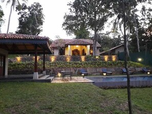 Una villa con piscina, mobiliario exterior y un patio bien iluminado.