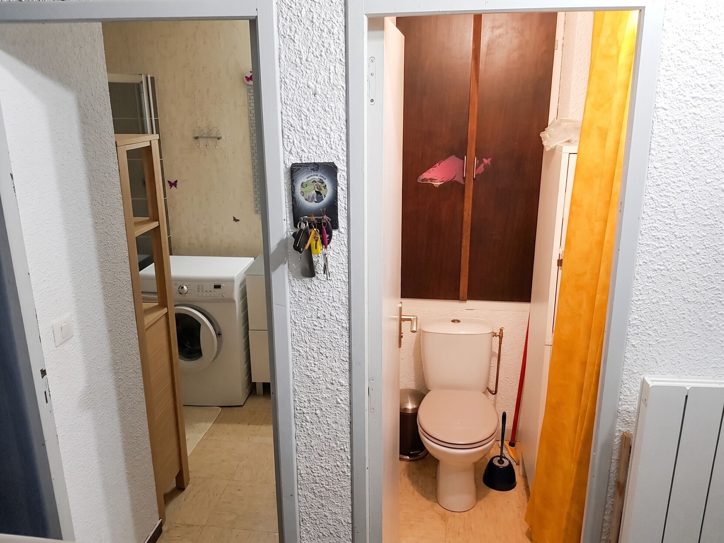 A compact bathroom with a washing machine, toilet, and a shower area.