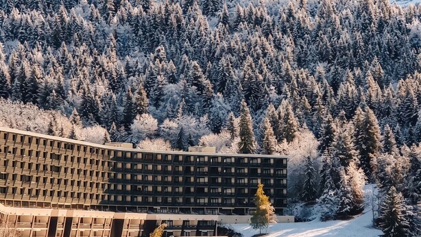 Ein modernes Gebäude mit einzigartigem architektonischen Design, umgeben von verschneiter Berglandschaft.