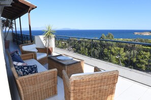 Un balcone con mobili in vimini, una pianta in vaso e vista sul mare.