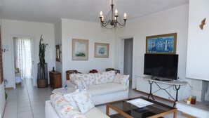 Una sala de estar con sofá, mesa de centro, televisor y candelabro.