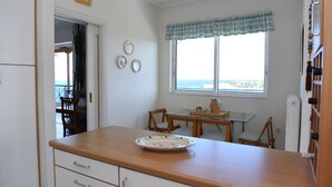 Una cocina con encimera de madera, una mesa de comedor con sillas y una ventana con vista al mar.