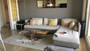 Un saló modern amb un sofà, una taula de centre de vidre i una prestatgeria.