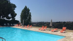 Una piscina amb gandules taronja i una vista de la ciutat de fons.