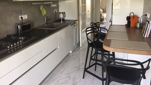 Una cuina moderna amb armaris blancs, un taulell negre i una taula de dinar de fusta amb quatre cadires.