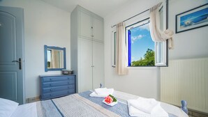 A bedroom with a bed, a dresser, a mirror, a window with curtains, and a radiator. - Apartment Tsilivi Blue Vista (Zakynthos)
