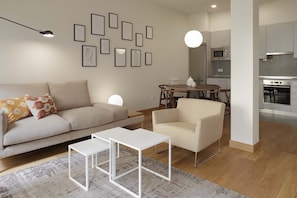 A modern living room with a sofa, coffee table, and a dining area with a table and chairs.