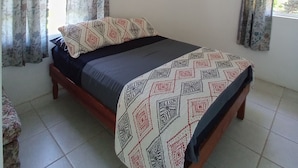 A bedroom with a bed, curtains, and a window.