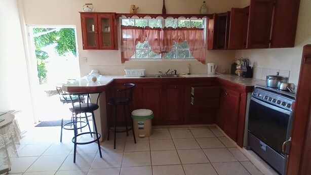 A kitchen with a stove, sink, and bar stools.