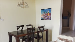A dining area with a wooden table and chairs, a chandelier, and a painting on the wall.
