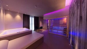 Un spa moderno con una bañera grande, un rincón de descanso y una camilla de masaje.
