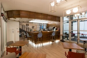Un café moderne avec des éléments décoratifs en bois, un bar et de grandes fenêtres offrant une vue panoramique.