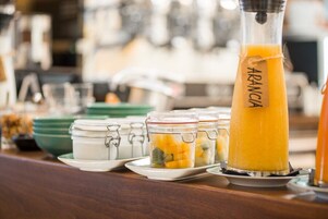 A breakfast bar with a tall glass pitcher labeled "ARANCIA" and several small jars with food items.