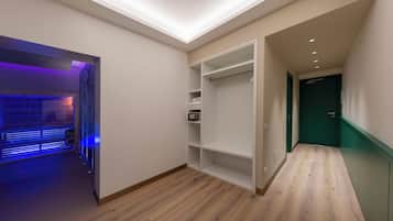Een moderne hal met houten vloer, een inbouwkast met planken, en een deur naar een andere kamer.