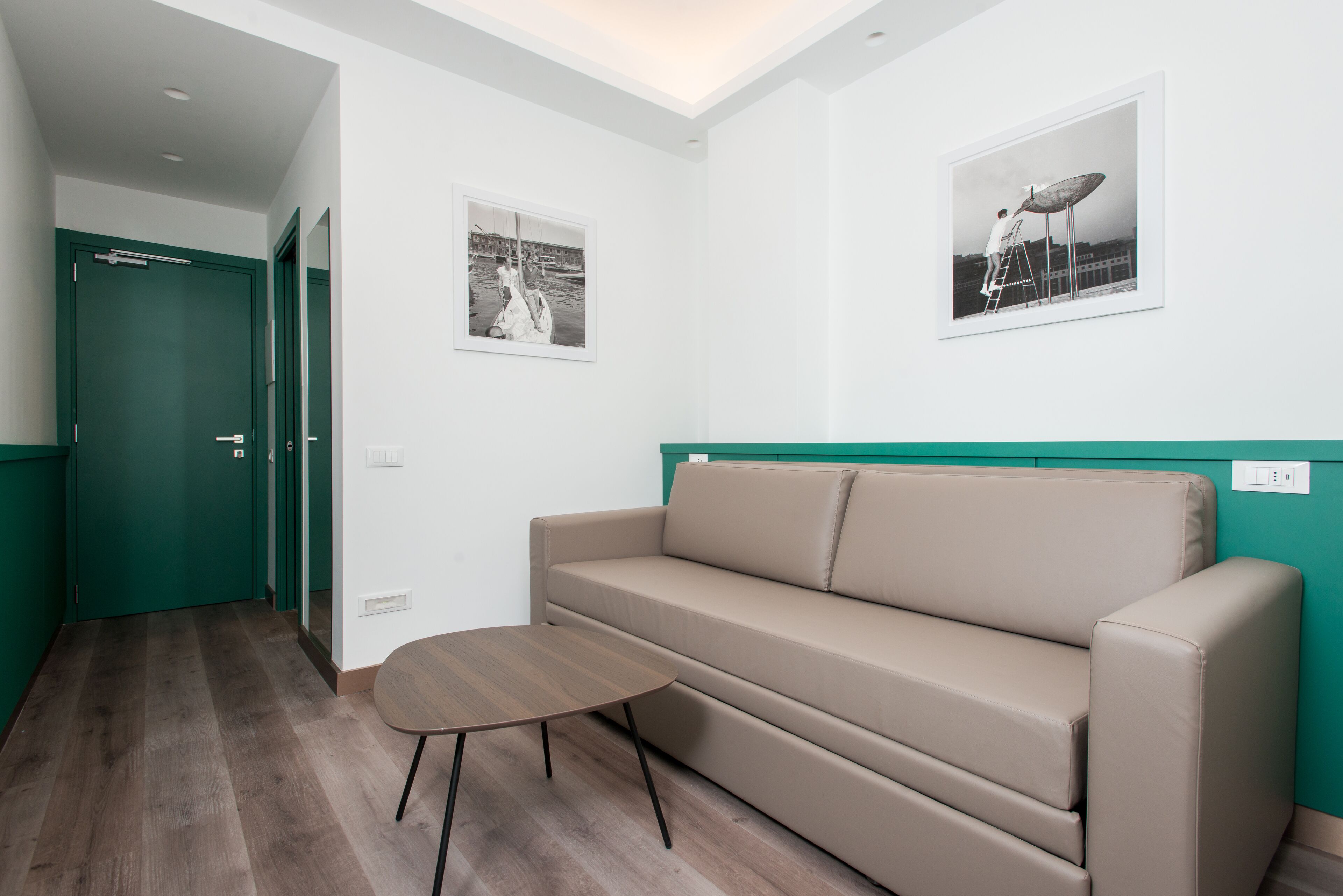 A modern room with a beige sofa, a small round table, and two framed pictures on the walls.