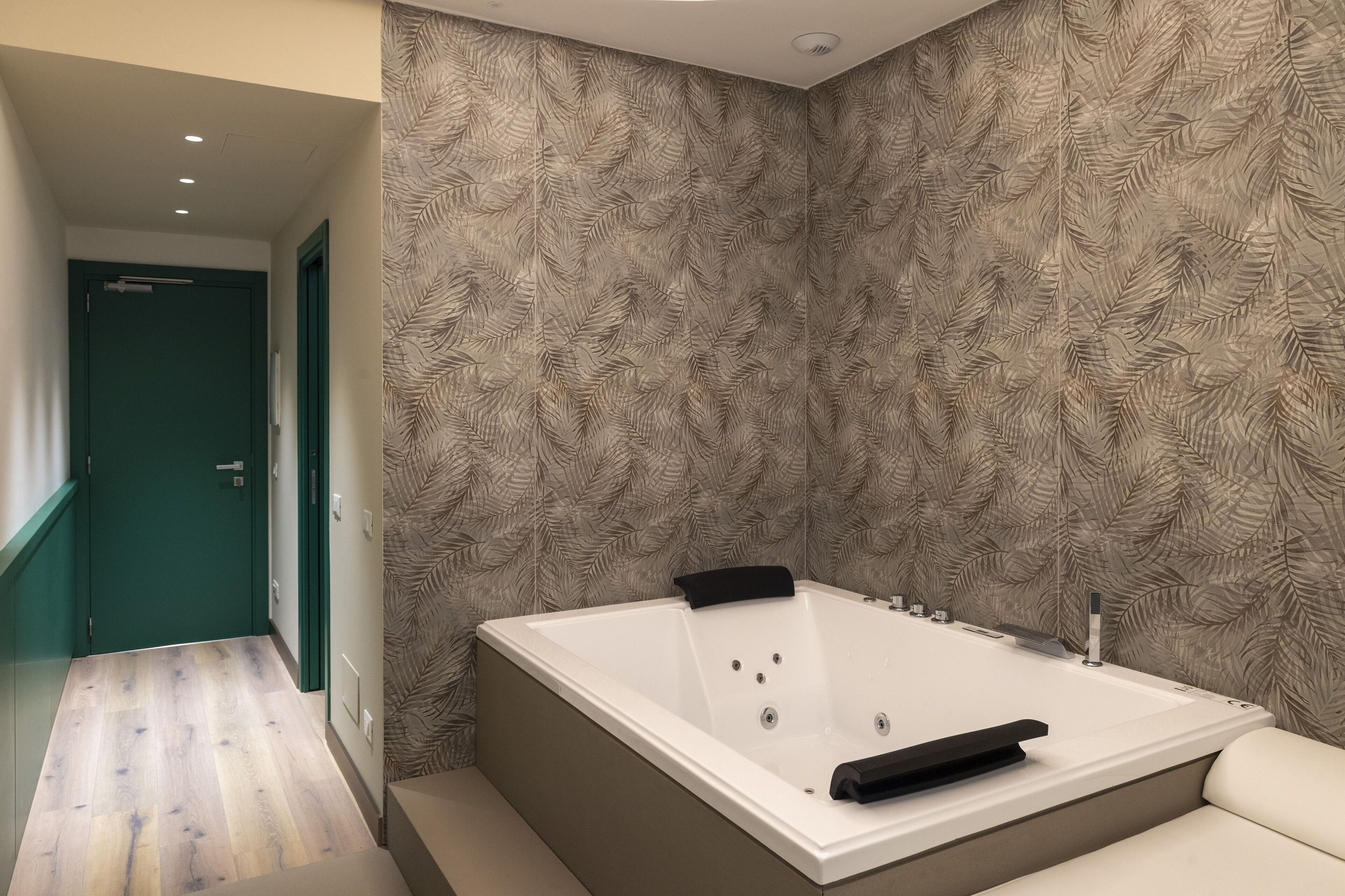 Un baño moderno con una bañera grande, suelo de madera y un papel tapiz estampado.