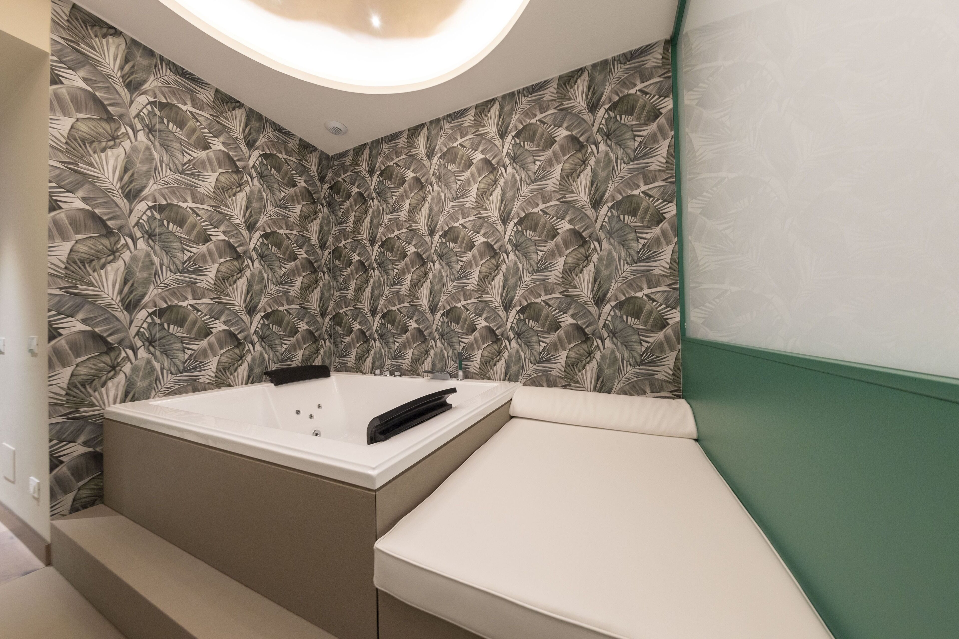 A modern bathroom with a large bathtub, a vanity, and a green accent wall.