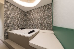 Un bagno moderno con una vasca da bagno ampia, un mobile lavabo e una parete verde decorativa.