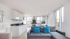 A modern apartment with a grey sofa, a dining table, and a kitchen area. - Spacious 2-Bed · Balcony · St Pancras · Sleeps 6 (London)