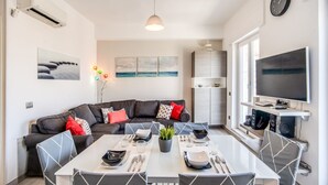 A modern living room with a dining table, sofa, TV, and artwork. - SeaView Apartment Sorrento center! (Sorrento)