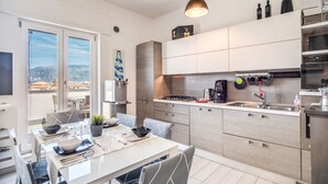 A modern kitchen with a dining area, large windows, and a view of the city. - SeaView Apartment Sorrento center! (Sorrento)