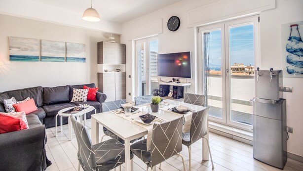A modern living room with a sofa, dining table, chairs, a TV, and a refrigerator. - SeaView Apartment Sorrento center! (Sorrento)