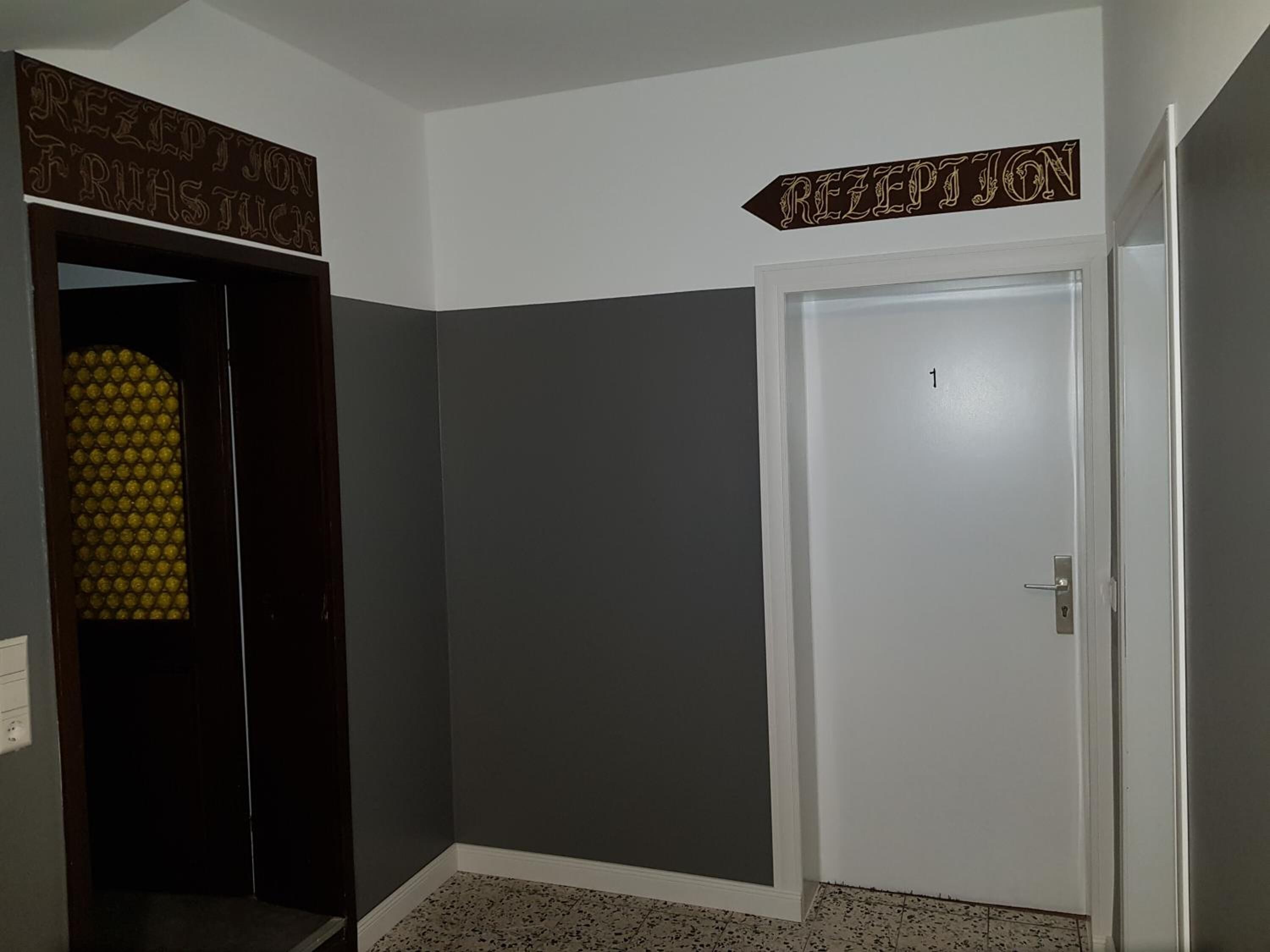 A hallway with a reception sign, a door labeled '1', and a door with a yellow patterned glass panel.